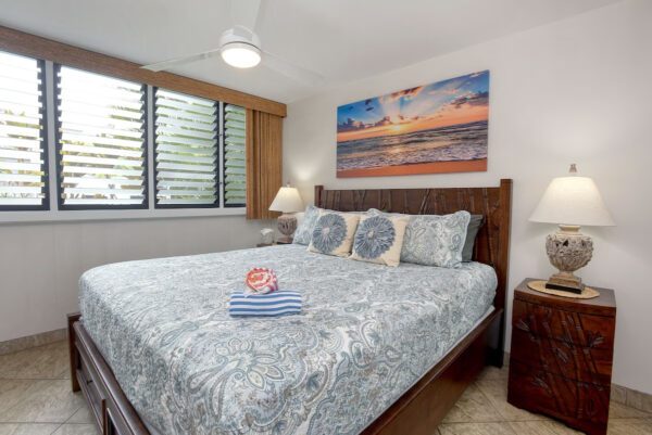 A bedroom with a bed, nightstand and window.