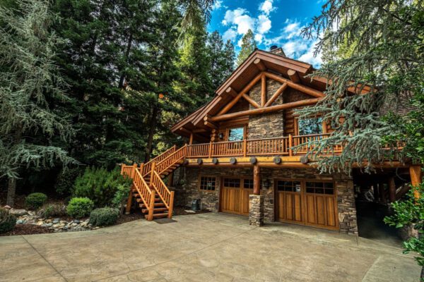 A large log cabin with stairs leading to the garage.