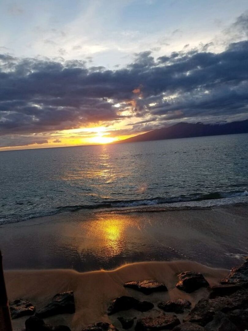 A sunset over the ocean with clouds in the sky.