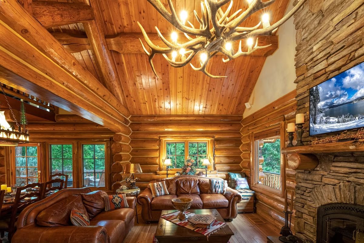 A living room with antler chandelier and wood paneled walls.