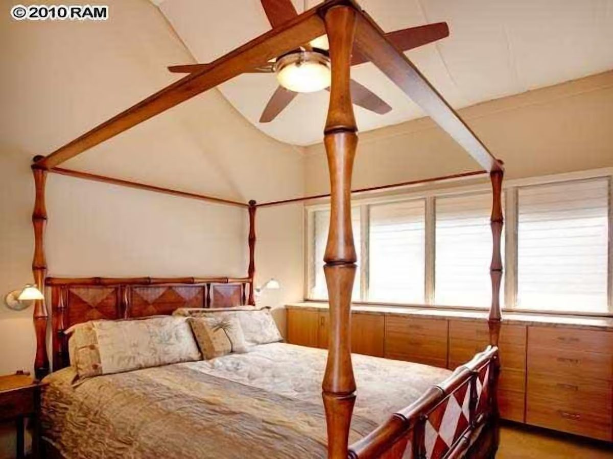 A bedroom with four poster bed and ceiling fan.