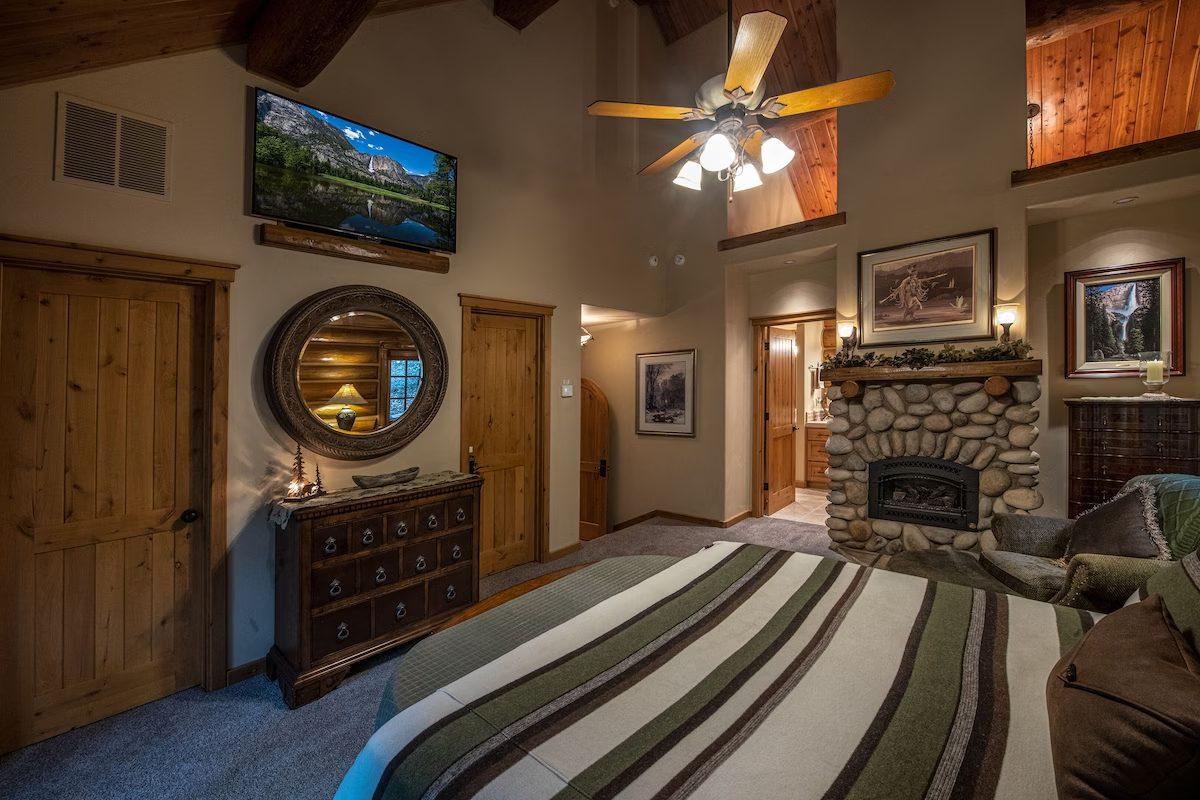 A bedroom with a bed, dresser and fireplace.