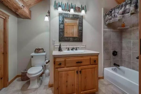 A bathroom with a toilet, sink and mirror.