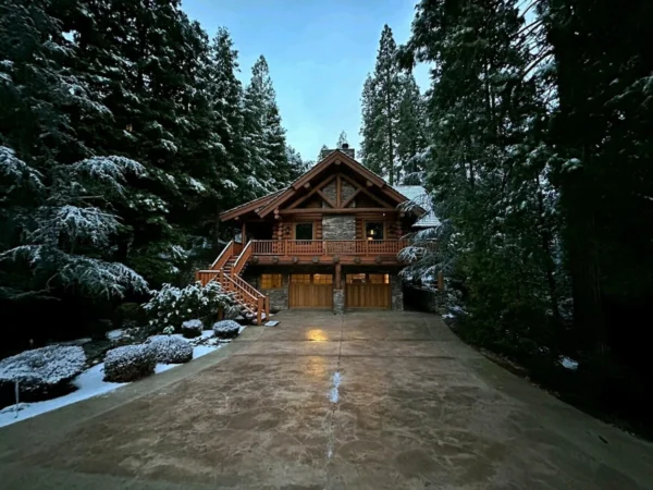 A house in the middle of snow covered trees.