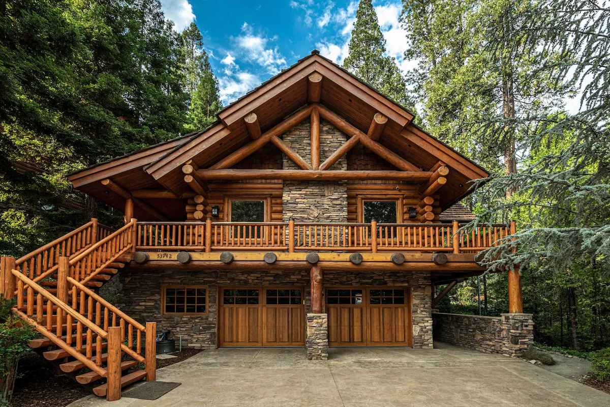 A large log cabin with stairs leading to the garage.