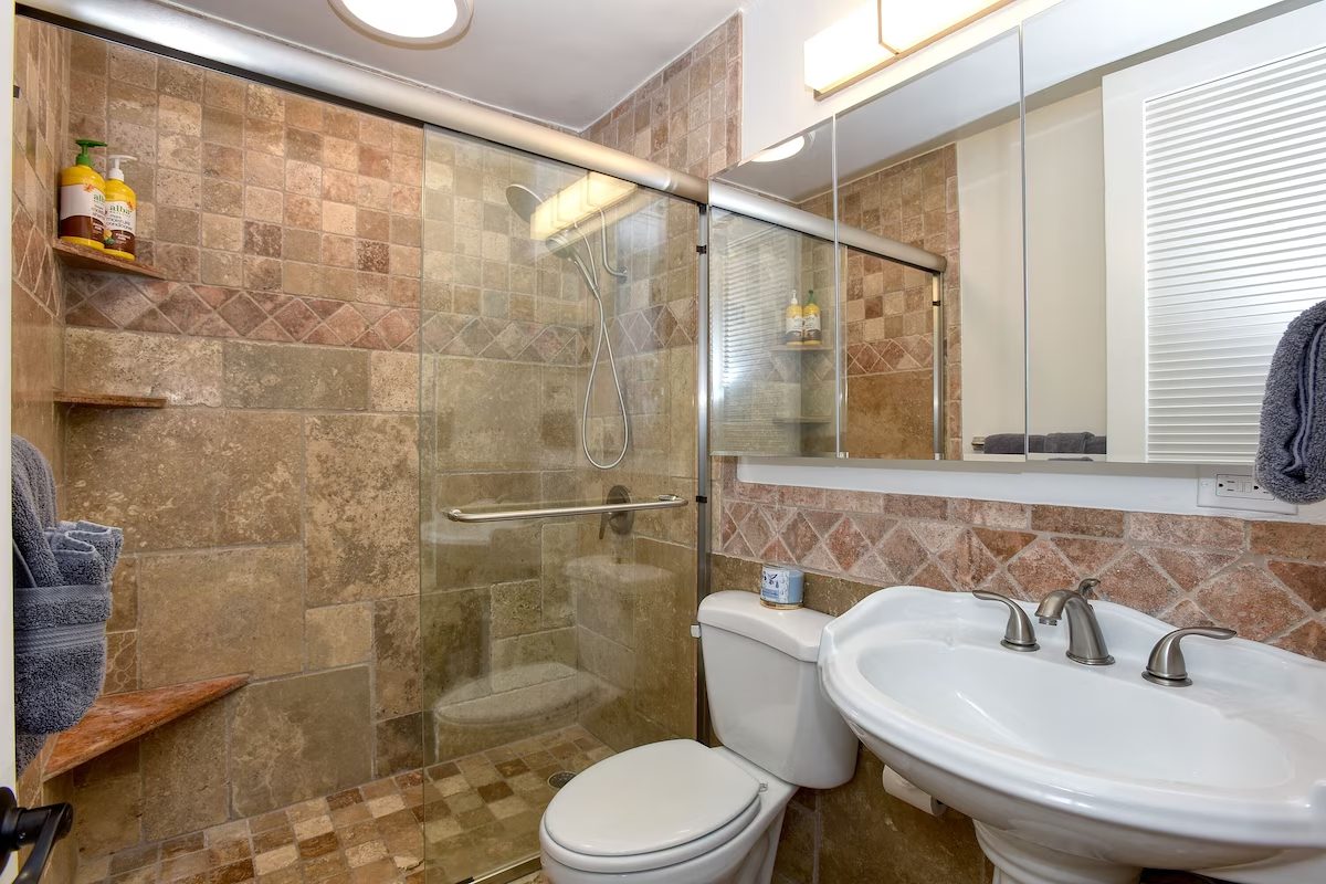 A bathroom with a toilet, sink and shower.