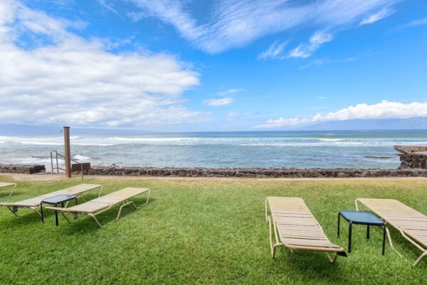 A lawn with three lounge chairs and one table