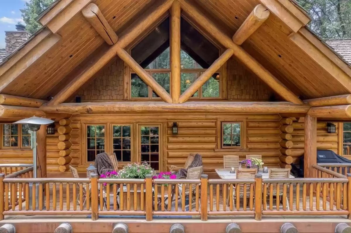 A large wooden house with many windows and furniture.