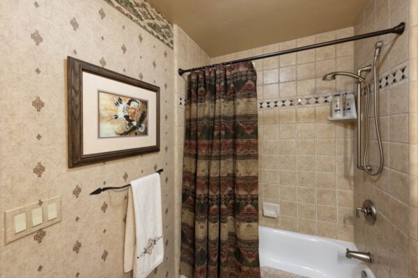 A bathroom with a tub, shower curtain and wall paper.