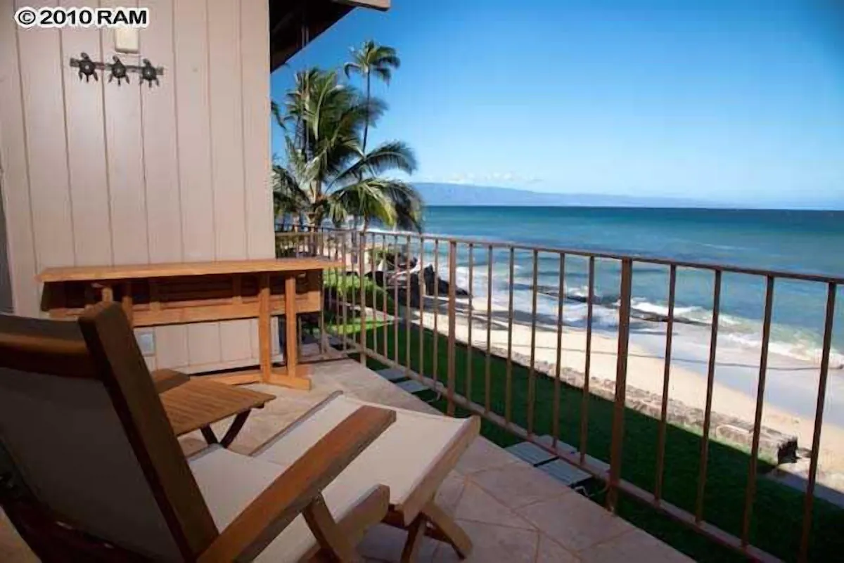 A balcony with chairs and a table on the beach