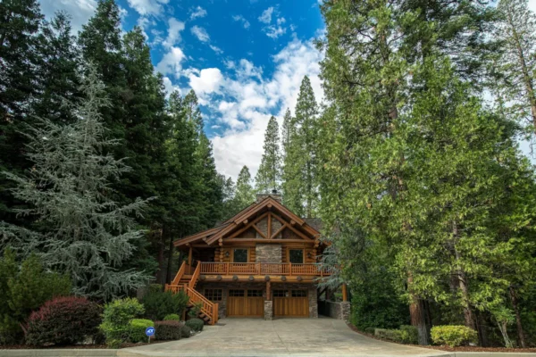 A house with two garage doors and trees in the background.