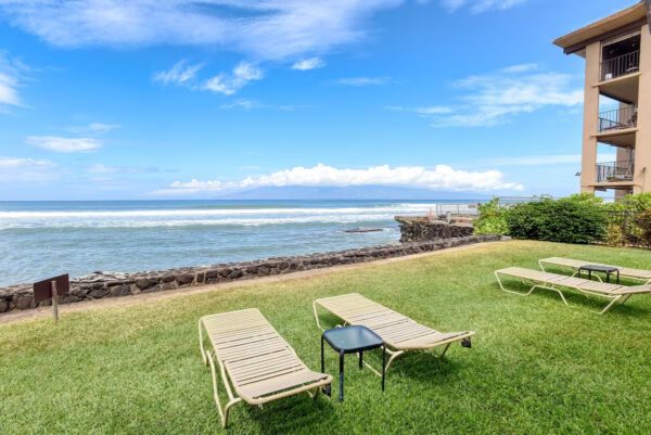 A lawn with two lounge chairs and a table in the grass.