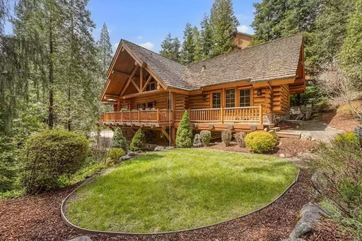 A large log cabin with a lawn in front of it.