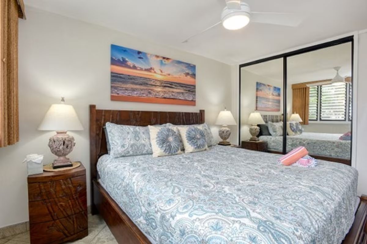 A bedroom with a bed, nightstand and mirror.