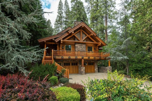 A log cabin with a stone wall and steps leading to the front door.