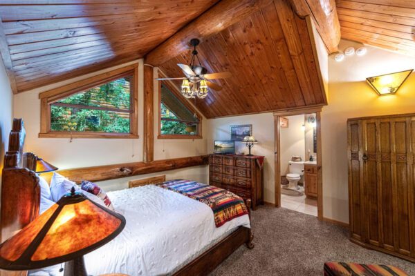 A bedroom with a bed, dresser and window.