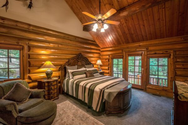 A bedroom with a bed, chair and ceiling fan.