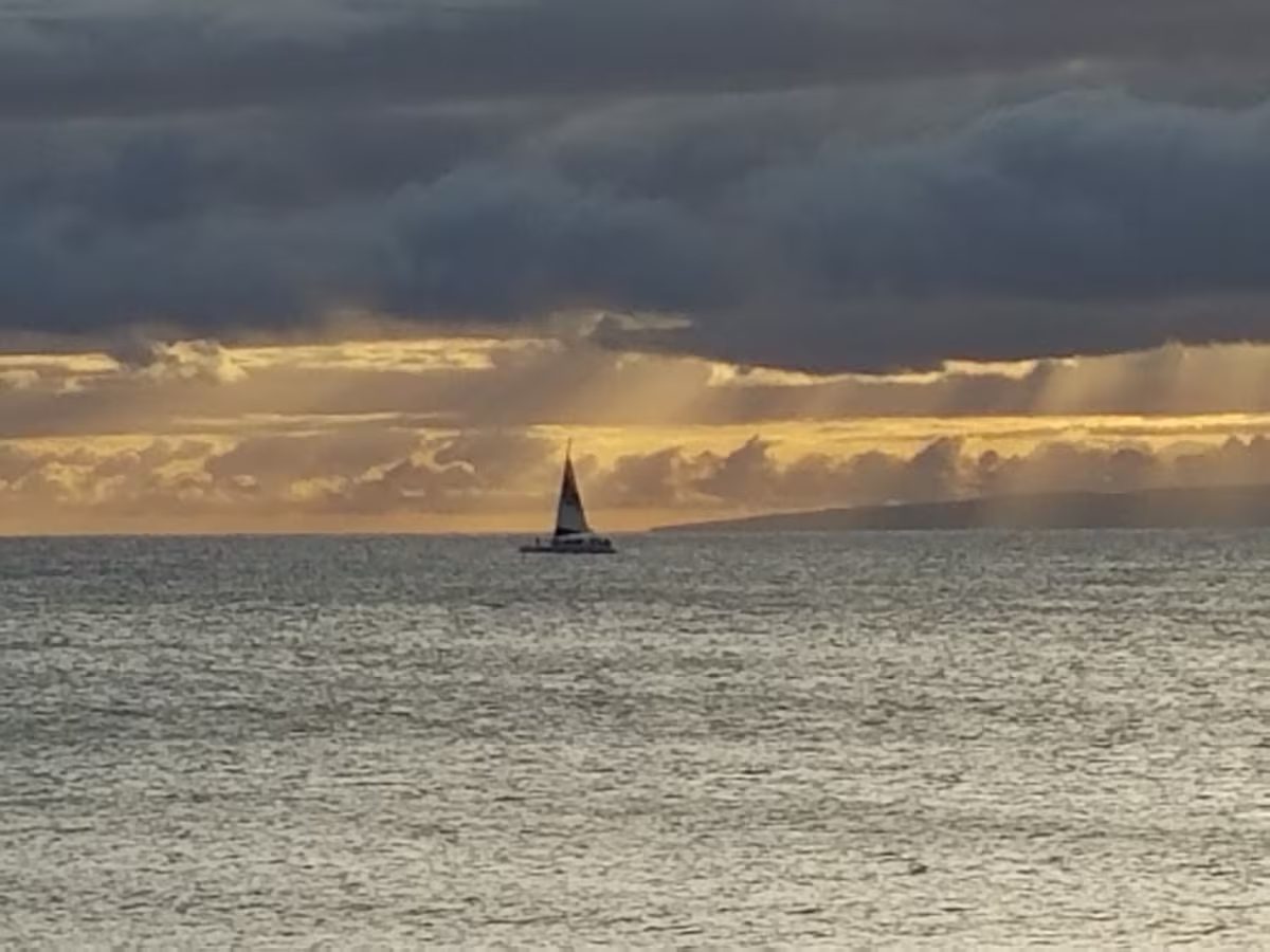 A sailboat is sailing in the ocean under cloudy skies.