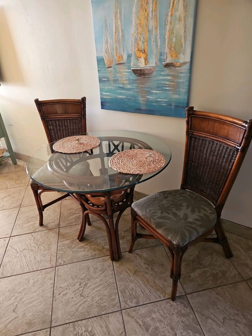 A table with two chairs and a painting on the wall.