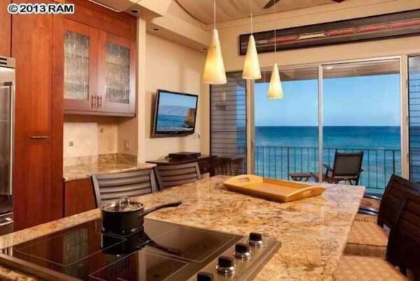 A kitchen with a view of the ocean and a flat screen tv.