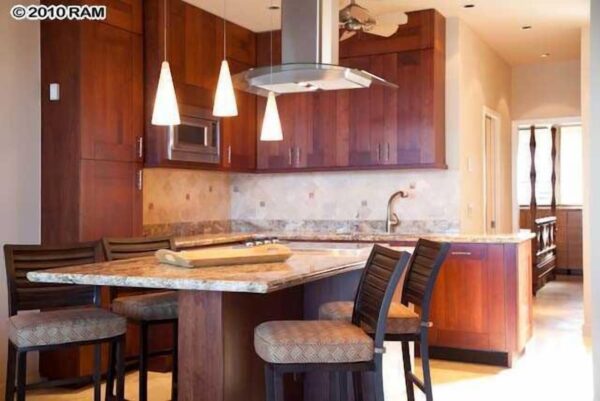 A kitchen with wooden cabinets and a marble island.