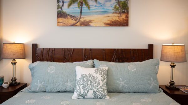 A bed with pillows and a painting on the wall.