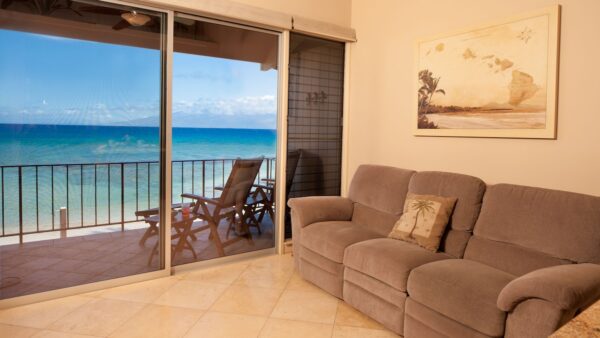 A living room with couches and chairs in front of the ocean.