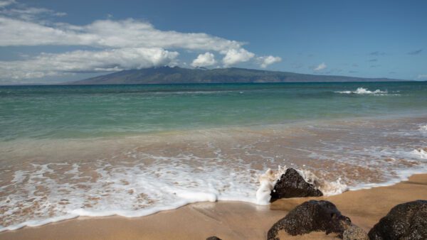 A beach with waves coming in from the ocean.