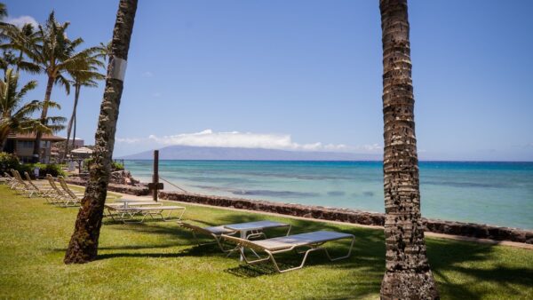 A lawn chair and table on the grass near the ocean.