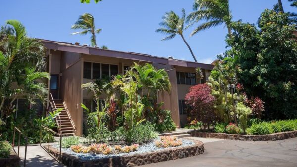 A building with plants and trees in front of it.