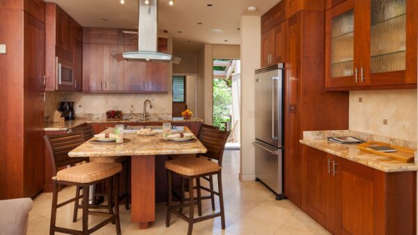 A kitchen with wooden cabinets and marble counter tops.