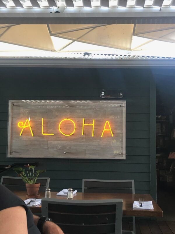 A neon sign that says aloha on the wall.