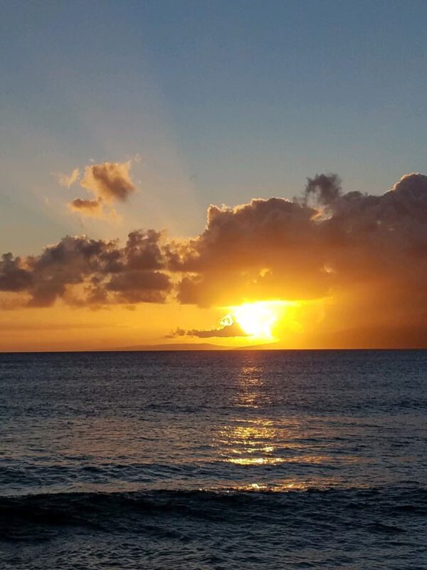 A sunset over the ocean with clouds in the sky.