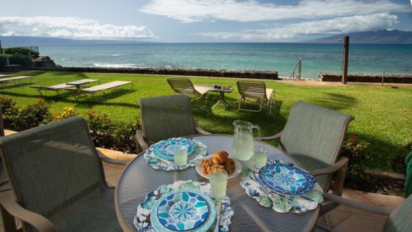 A table with plates and cups on it near the ocean.