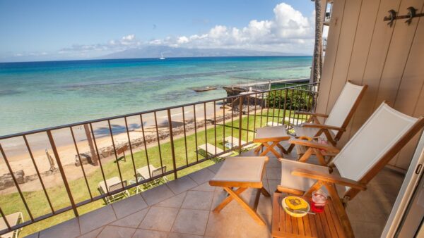 A balcony with chairs and tables overlooking the ocean.