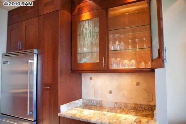 A kitchen with wooden cabinets and marble counter tops.